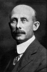 Photo d'un homme émacié, en partie chauve, avec une grosse moustache.