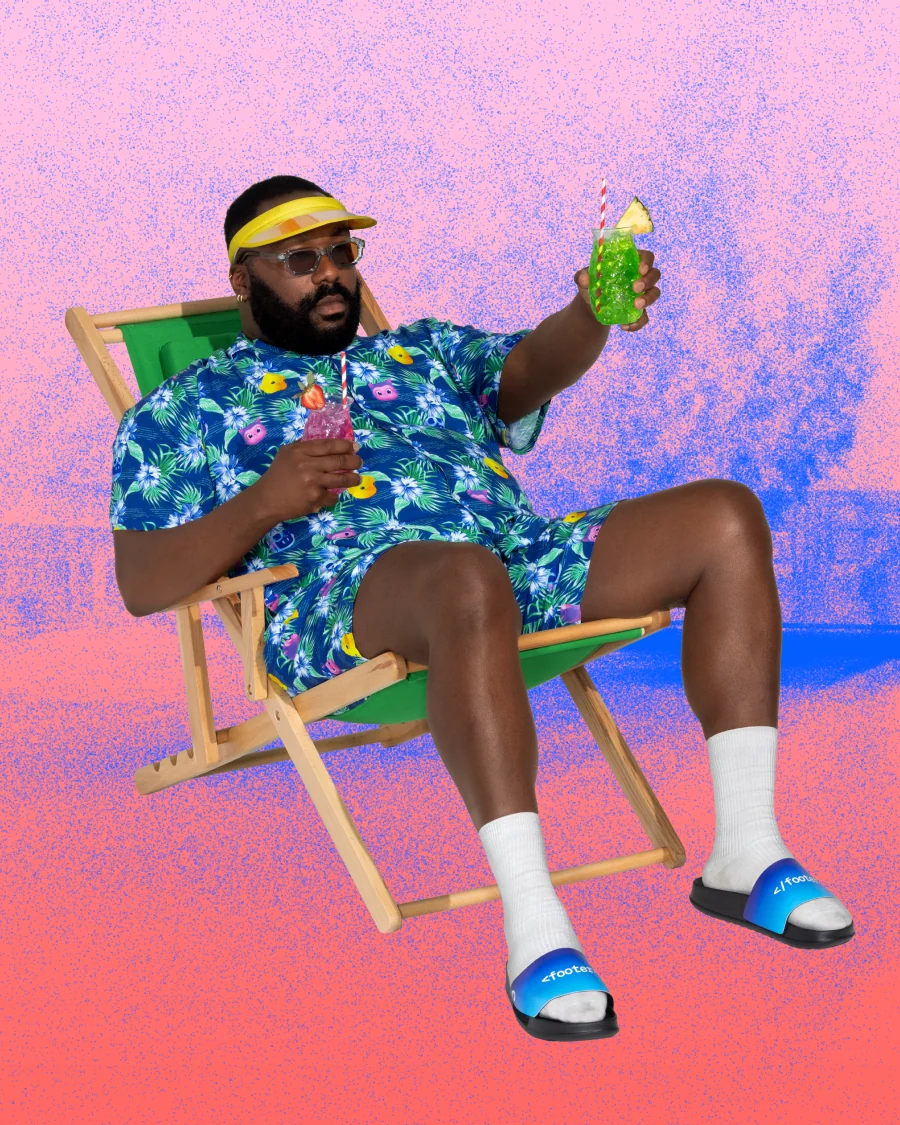 Man in a cabana shirt and short sitting on a chair, holding drinks.