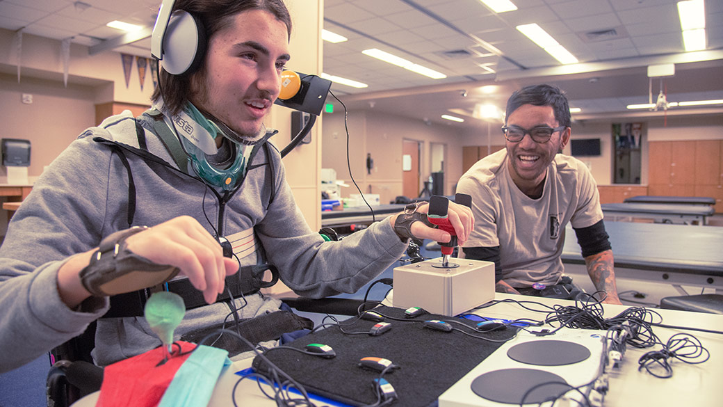 A man using joysticks that a re plugged into the XBOX Adaptive Controller