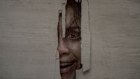 Deadite Thya's face peering through hole in a wall Shining-style in Evil Dead Burn