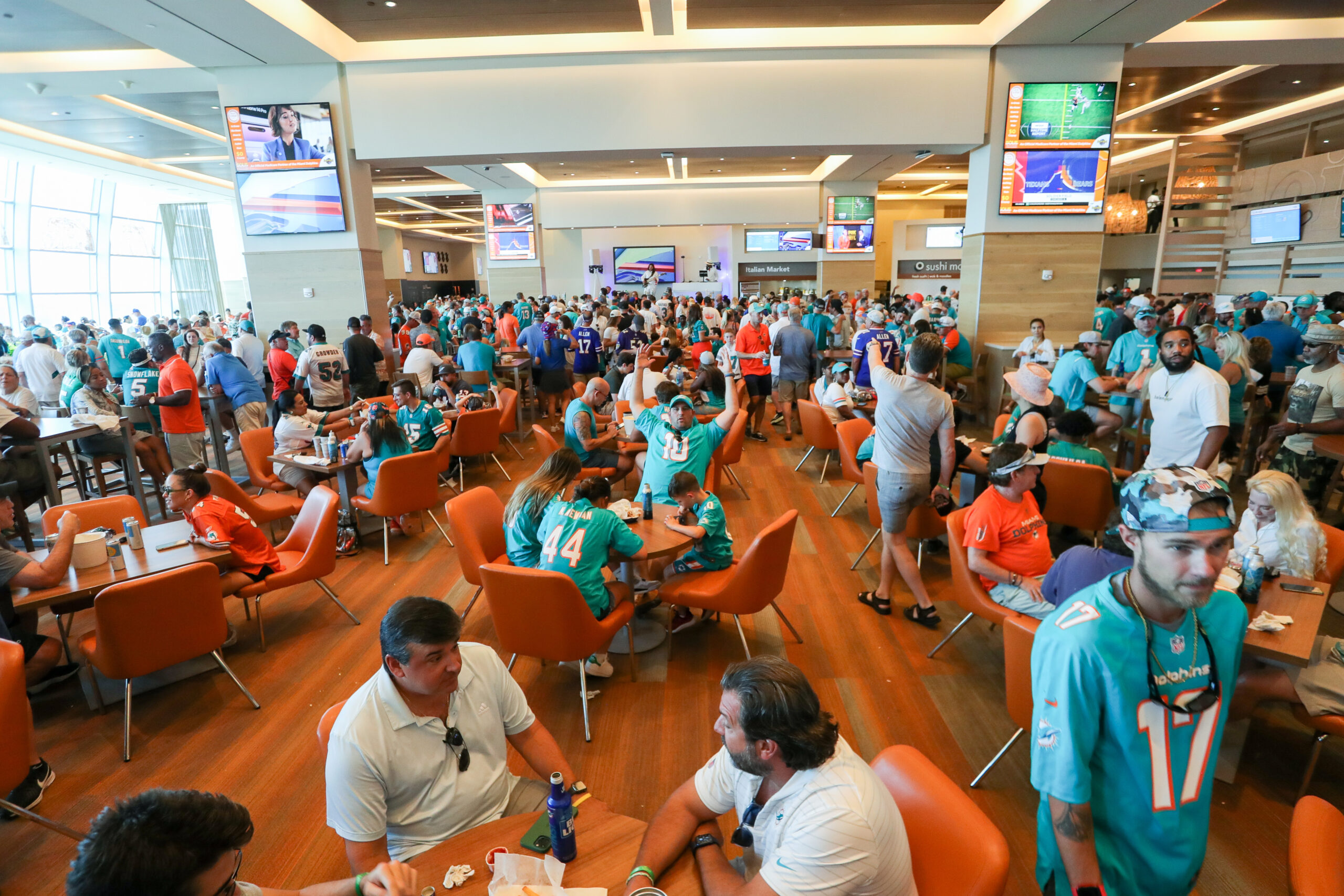 Bills Dolphins Football Dozens of fans in Dolphins gear gather together on the suite level.
