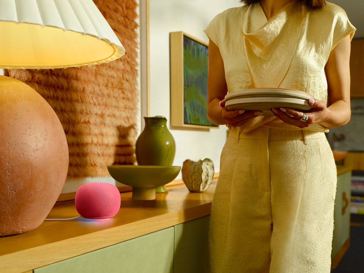 A Google Home Speaker sits on a credenza next to a bowl, vase and lamp.